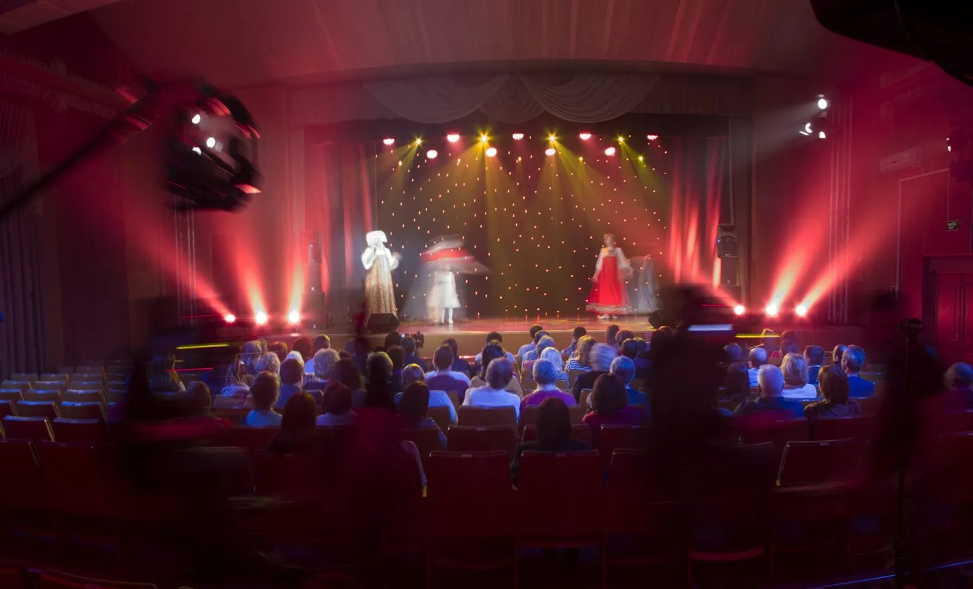 Audience gathered inside a theater during a live cultural performance.
